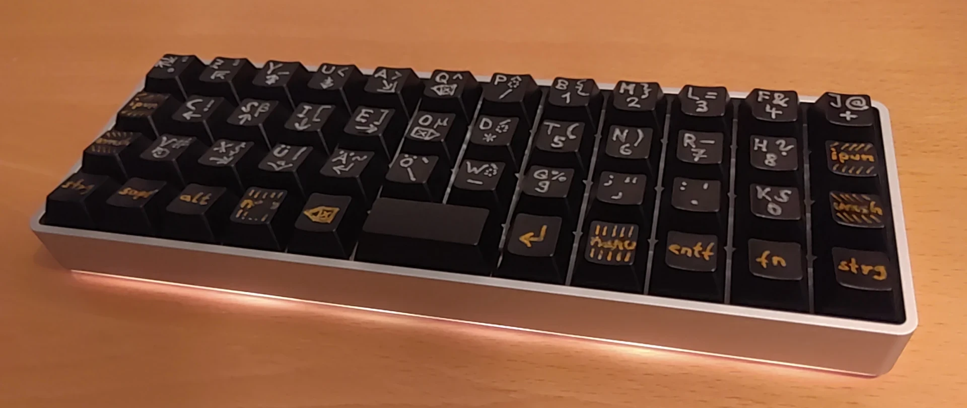 12x4 ortholinear keyboard with the Firmlynoted layout, handwritten silver and gold labels on black keycaps.